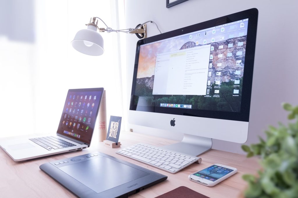 Electronic devices next to an iMac on a desk.
